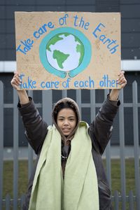 Eine Frau hält ein Protestschild hoch auf dem steht: Take care of the earth, take care of each other. Foto: freepik