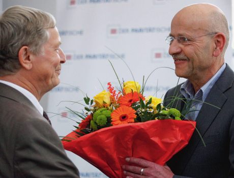 Foto mit zwei Männern. Links Dr. Eberhard Jüttner, der dem neben ihm stehenden Prof. Dr. Rosenbrock einen Blumenstraß überreicht.