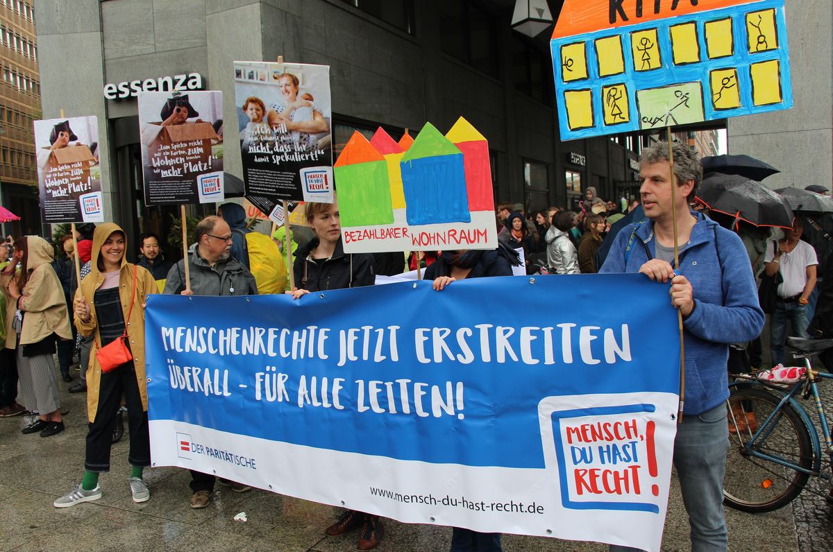 Foto mit Menschen auf einer Demonstration, die ein Abnner mit der Aufschrift "Menschenrechte jetzt erstreiten überall - für alle Zeiten!".