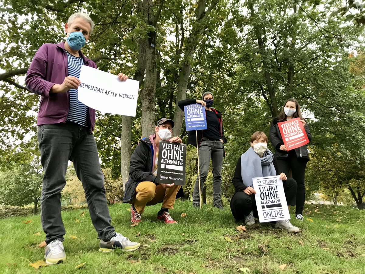 Eine Gruppe von Menschen steht zusammen mit "Vielfalt ohne Alternative"-Schildern
