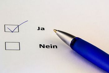 2 Kästchen "ja" und "nein", "ja" angekreuzt, Kugelschreiber