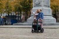 Zwei junge Frauen mit Rollator machen ein Selfie vor einer Statue