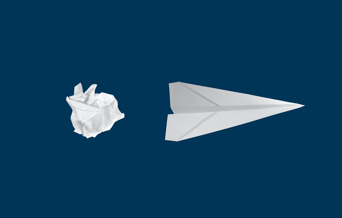 Zerknülltes Papier und ein Papierflieger