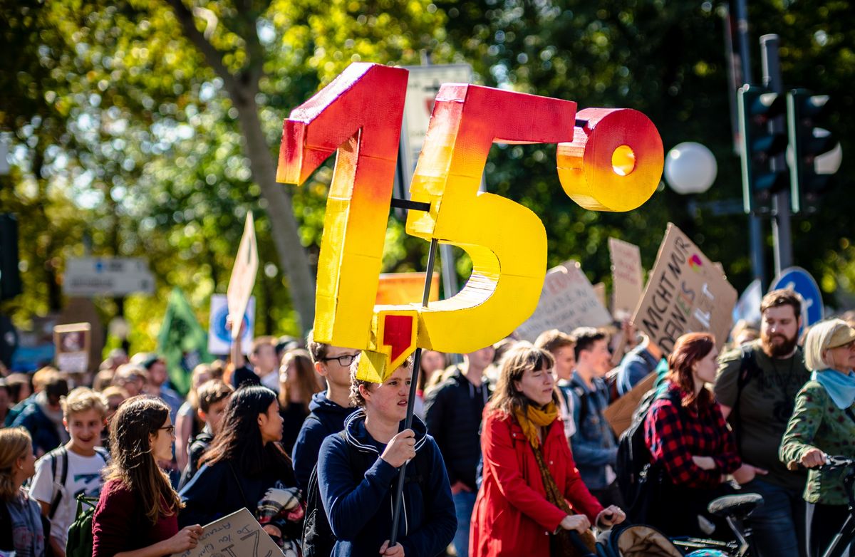 Jemand hält auf einer Demonstration große Ziffern hoch: 1,5 Grad.