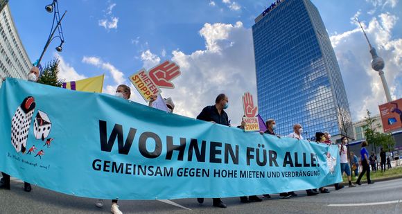 Demonstrationszug mit einem Transparent "Wohnen für alle" vor dem Berliner Fernsehturm