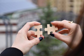 Zwei Hände, in jeder ein Puzzelteil, die Telie noch nicht verbunden.