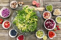 Das Bild zeigt frisches Obst und Gemüse, wie z.B. Salat, Pilze, Erdbeeren oder Heidelbeeren in kleinen Schälchen von oben.