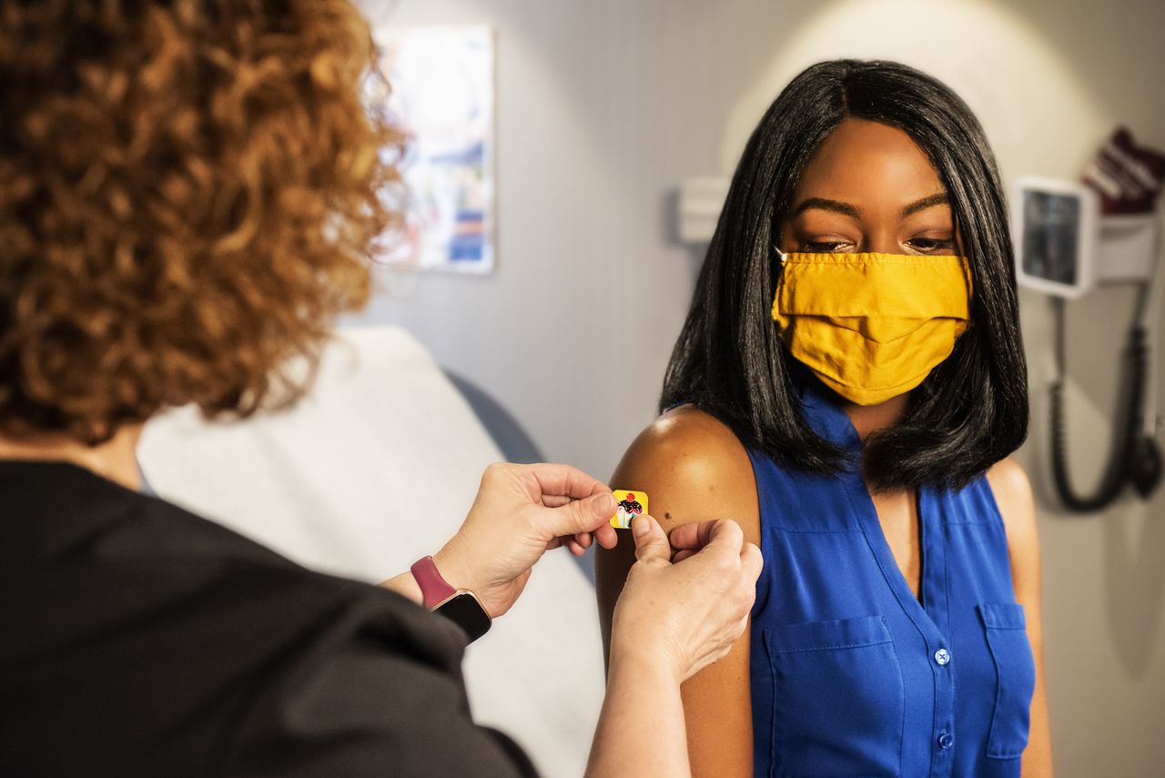 Eine Frau bekommt nach einer Impfung ein Pflaster auf den Arm geklebt.