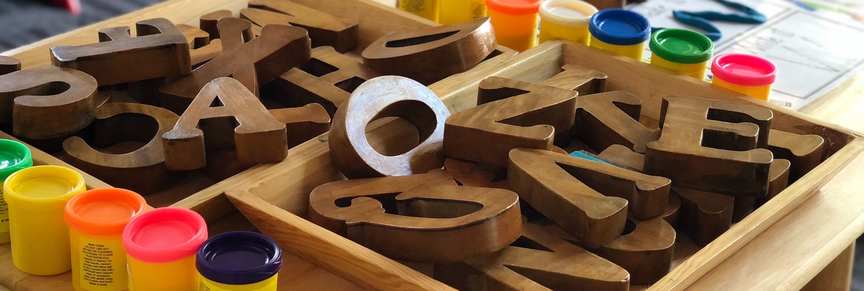 Verschiedene Spielzeuge wie Holzbuchstaben und Knete stehen auf dem Tisch einer Kita zur Auswahl