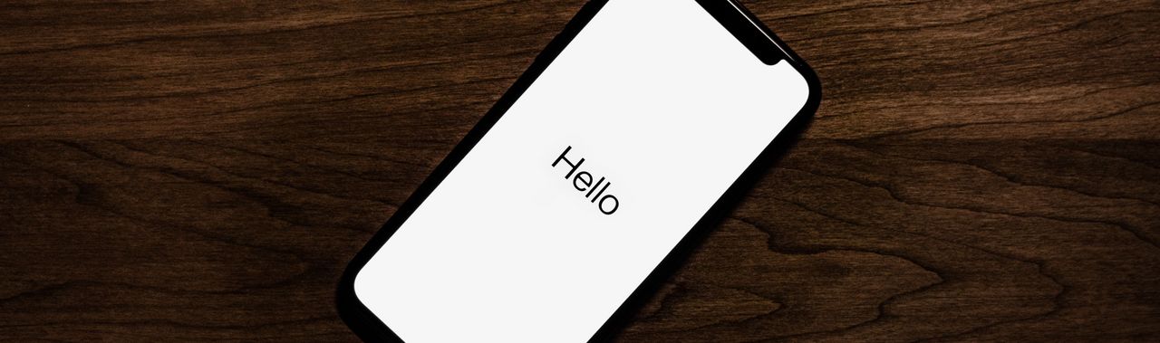 Smartphone auf einem einem Tisch: Auf dem Bildschirm steht groß "Hello"