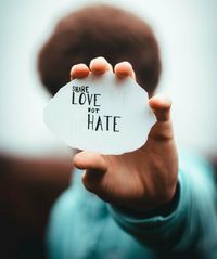 Hand hält ein Blatt mit der Aufschrift "Share Love not Hate".