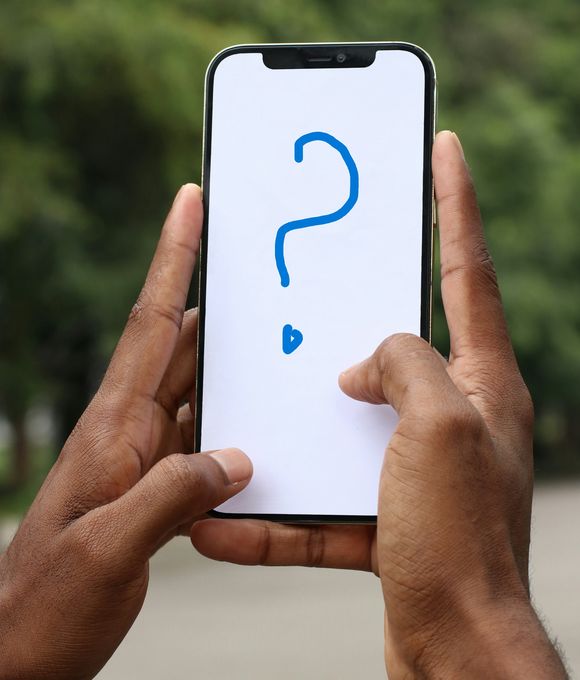 zwei Hände, die ein Smartphone halten, auf dem ein blaues Fragezeichen vor einem weißen Hintergrund abgebildet ist