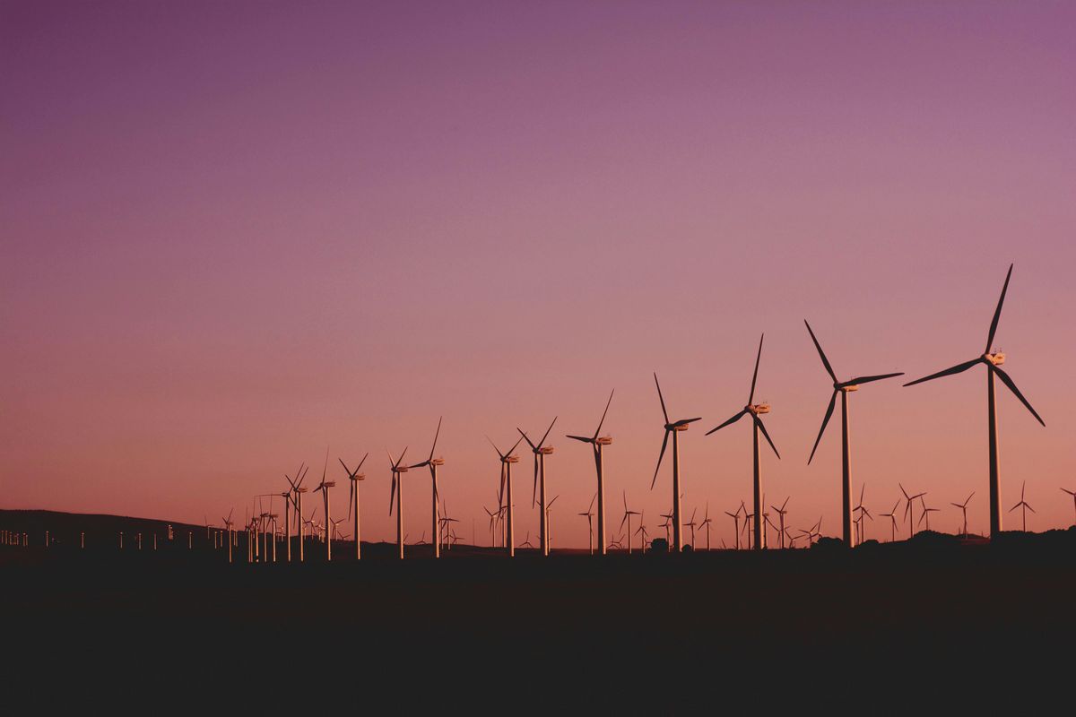 Windräder in einer Reihe vor einem Himmel in der Abenddämmerung