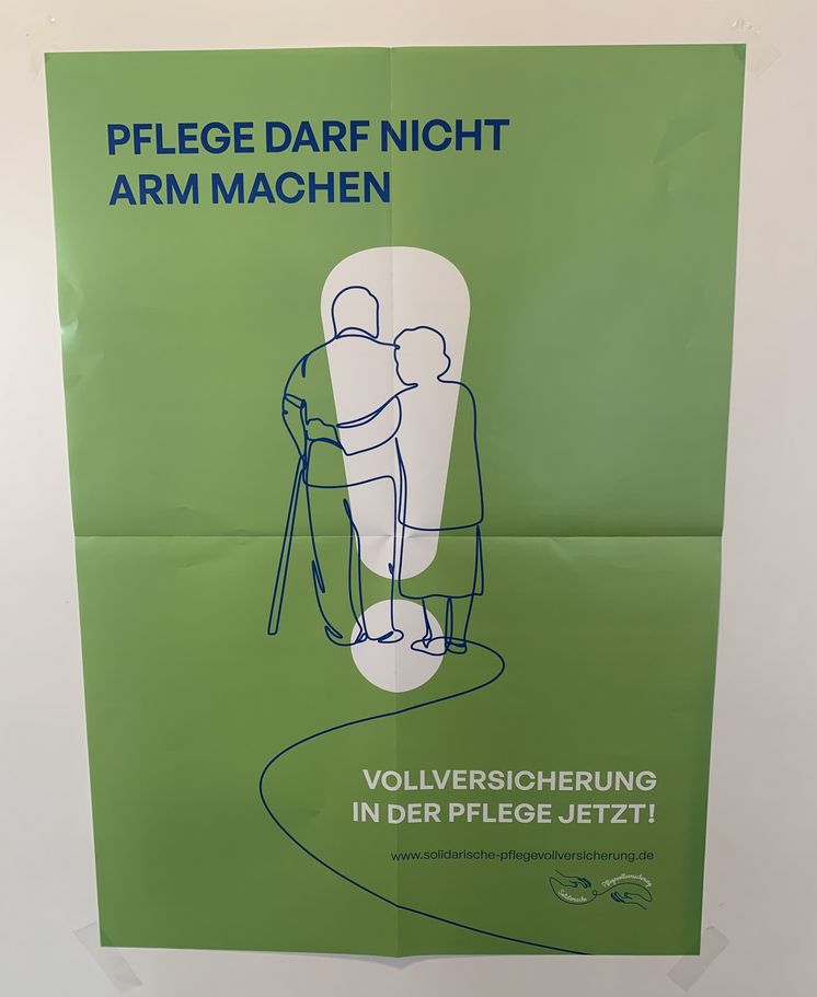 A2-Plakat_Pflegevollversicherung Vor grünem Hintergrund ist ein großes weißes Ausrufezeichen zu sehen und davor sind zwei ältere Personen gezeichnet. Links oben steht in blauer Schrift "Pflege darf nicht arm machen" und rechts unten in weiß "Vollversicherung in der Pflege, jetzt!"