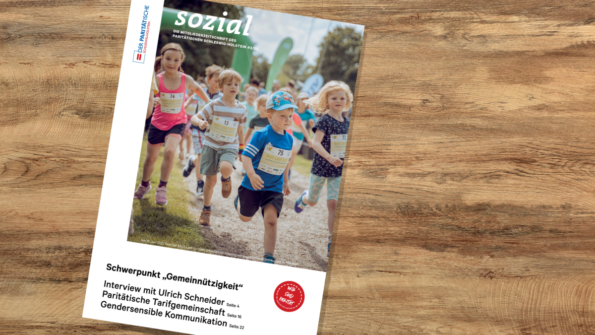 Auf einem Tisch liegt ein Magazin mit, auf dem rennende Kinder zu sehen sind. Titel des Magazins: sozial – die Mitgliederzeitschrift des Paritätischen Schleswig-Holstein 