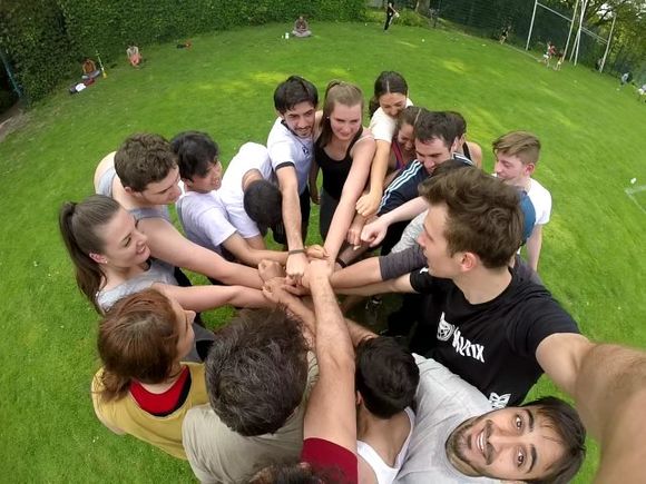 Selfie einer Gruppe Menschen, die im Kreis steht und die Hände übereinanderlegt