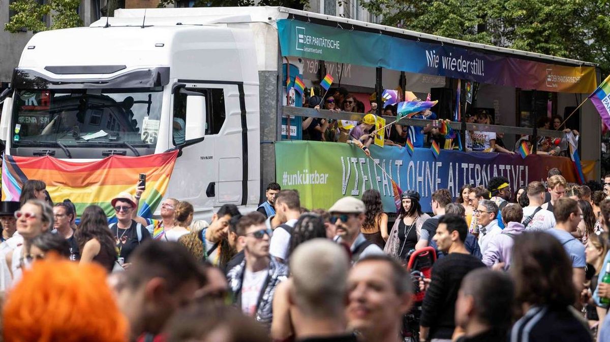 Ein Paradetruck mit vielen Regenbogenflaggen auf einer großen Demo.
