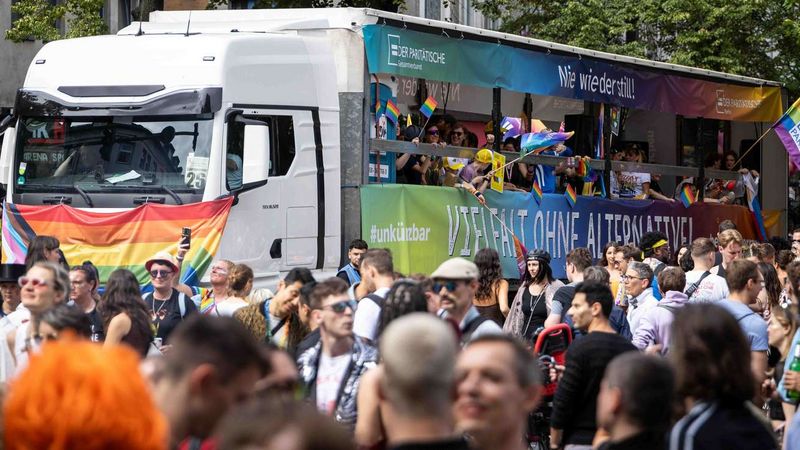 Ein Paradetruck mit vielen Regenbogenflaggen auf einer großen Demo.