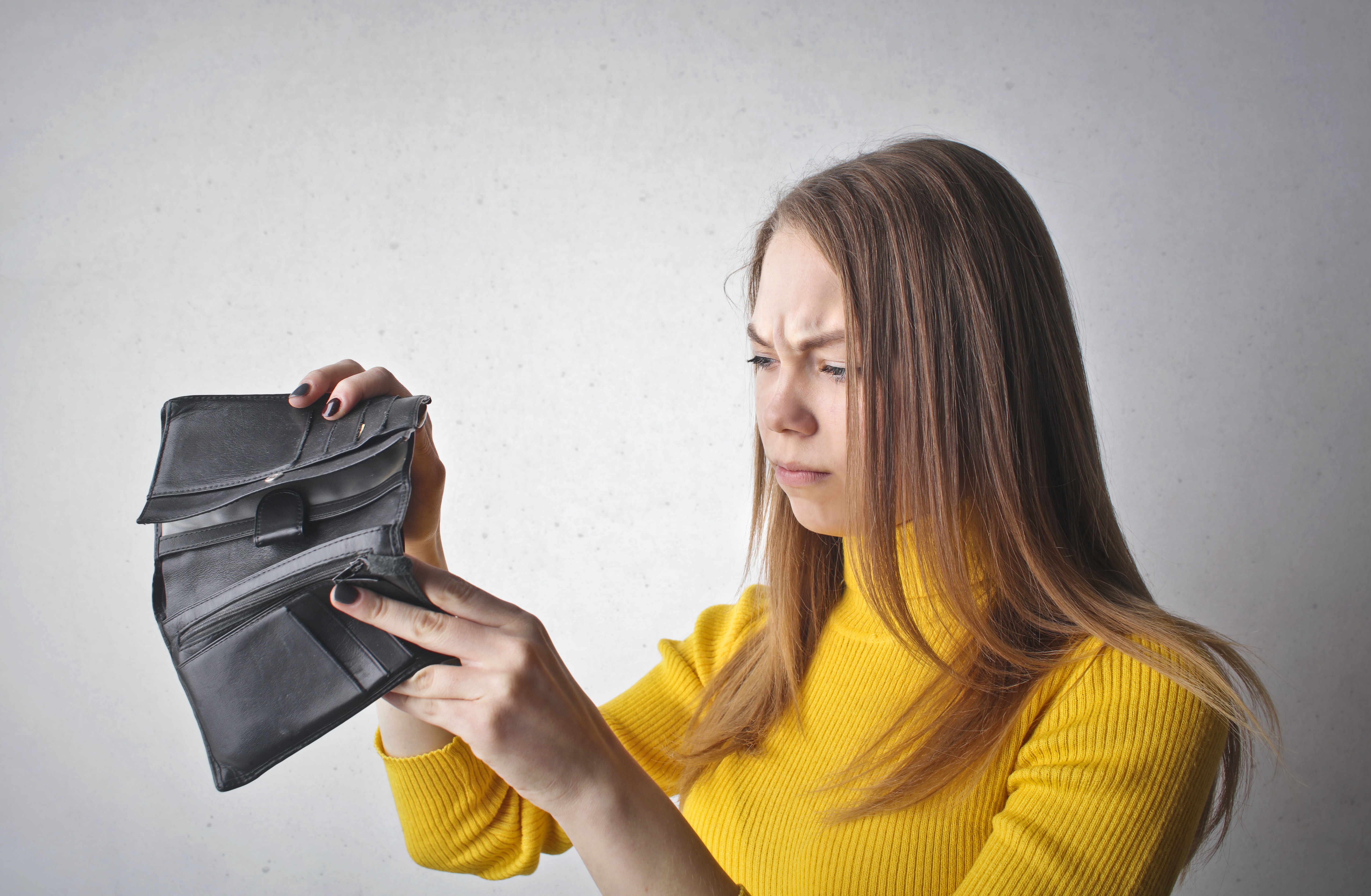 Eine Frau ärgert sich über ihren leeren Geldbeutel.