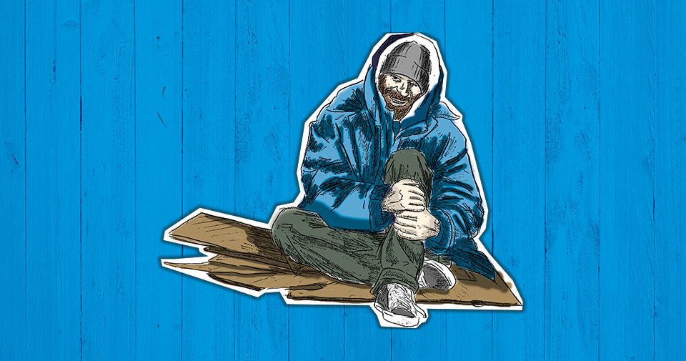 Ein wohnungsloser Mensch sitzt mit dicker Jacke und Wollmütze auf Pappstücken.