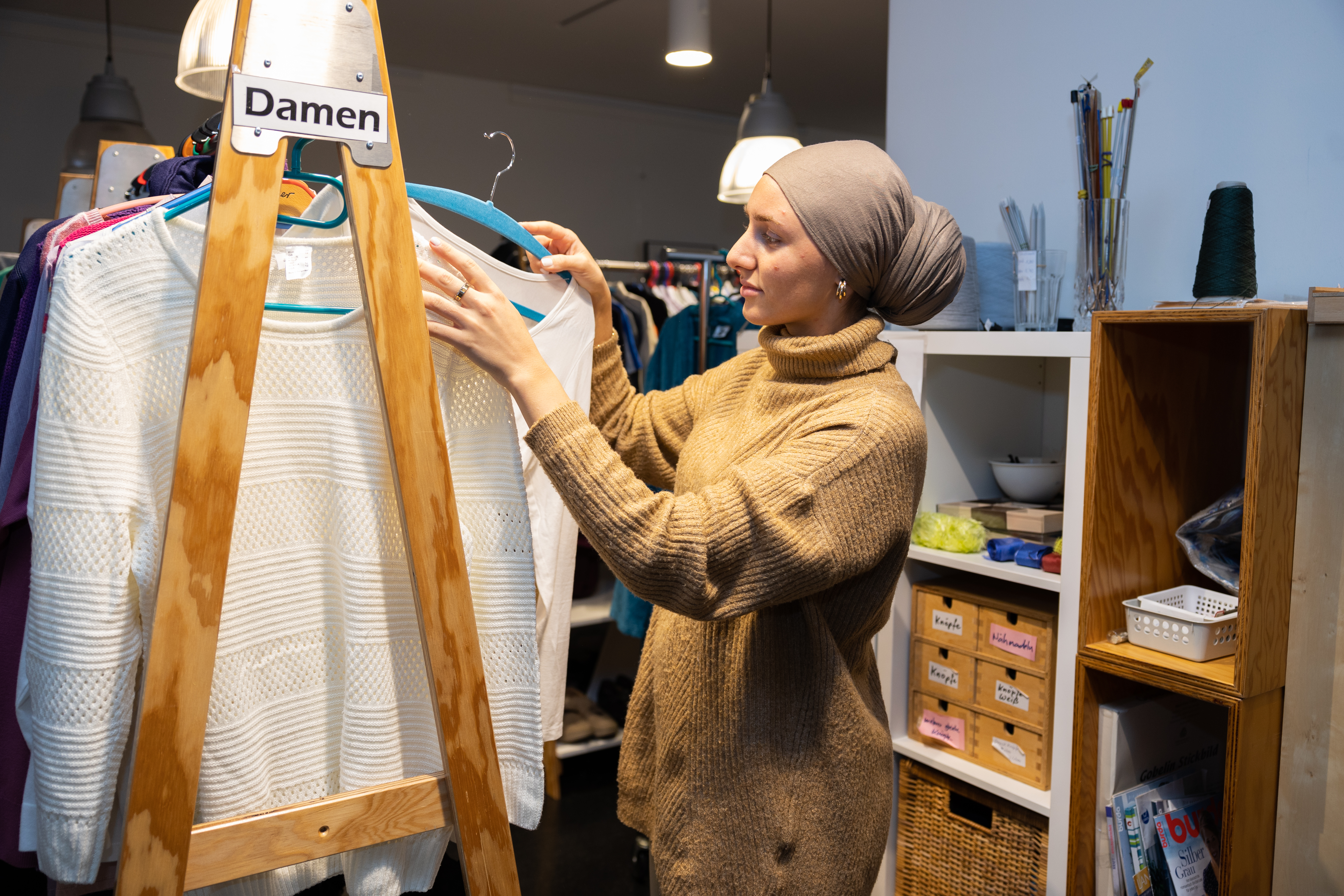 Das Bild zeigt eine junge Frau an einem Kleiderständer im Kaufhaus Hin und Weg