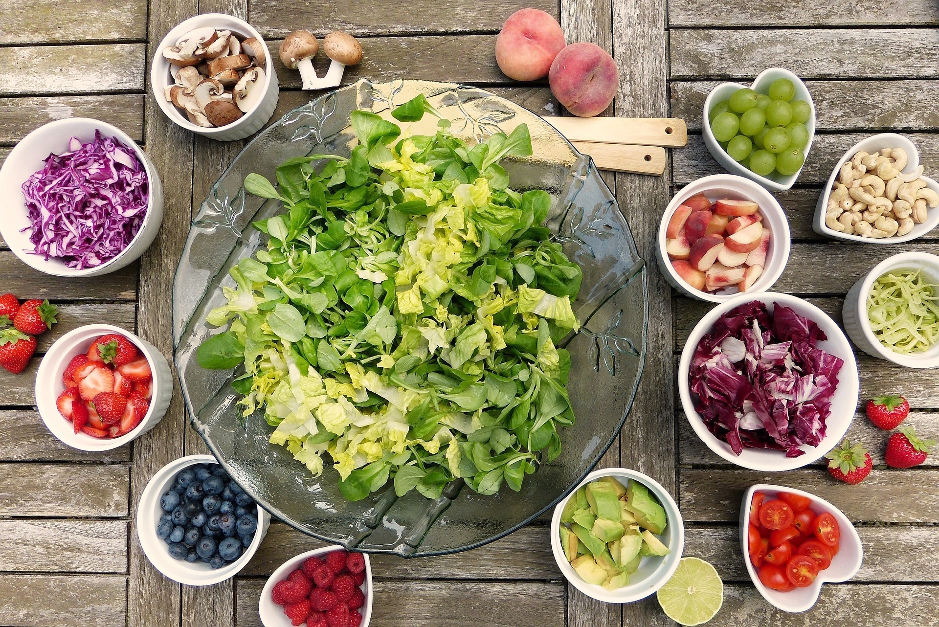 Das Bild zeigt frisches Obst und Gemüse, wie z.B. Salat, Pilze, Erdbeeren oder Heidelbeeren in kleinen Schälchen von oben.